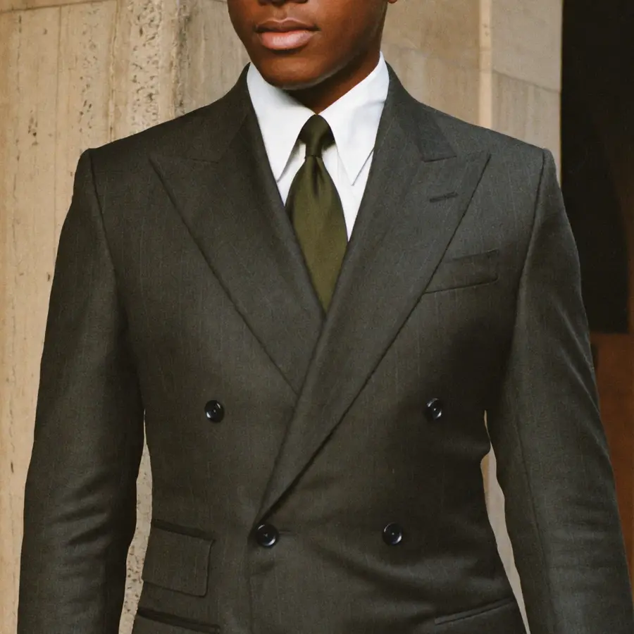 Peak lapels and buttons of a double-breasted jacket with an olive silk tie